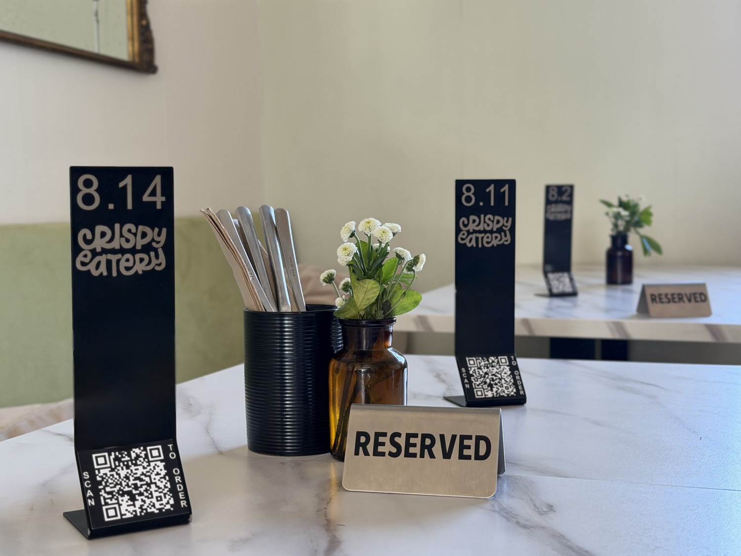 Several Crispy Eatery café tables set with branded QR ‘Scan to order’ stands during service.